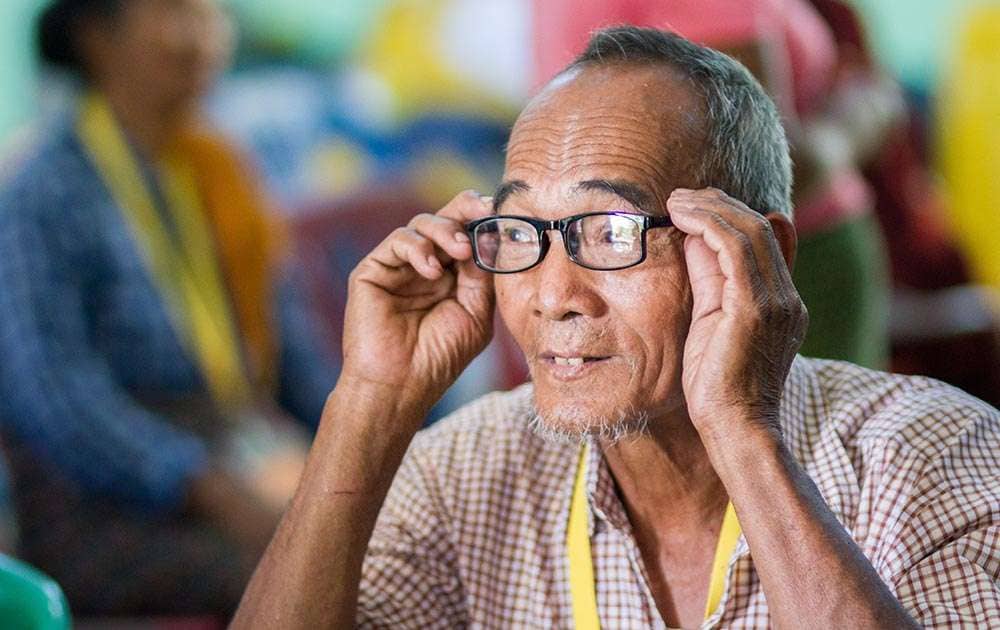 A senior man trying on a new pair of black rectangular eyeglasses