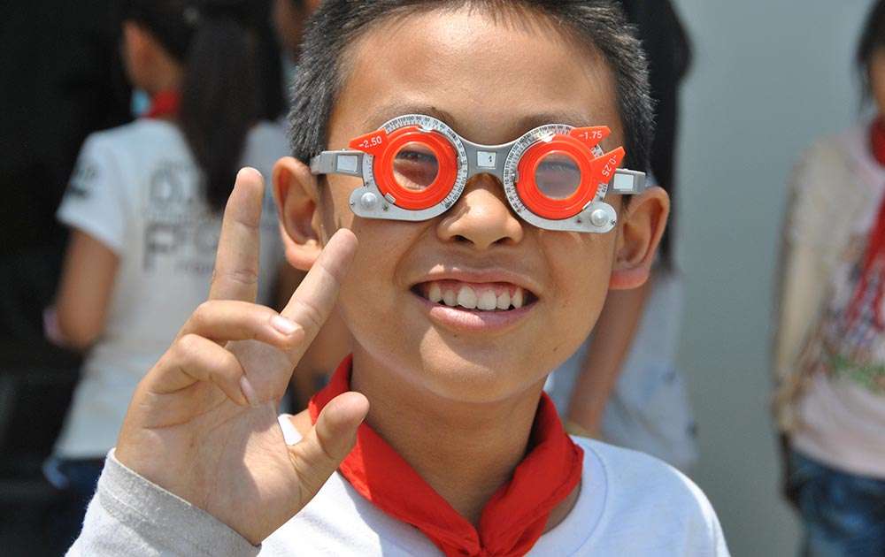 A child with a red scarf wearing orange and gray optical trial glasses