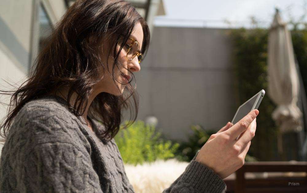 A woman with brown hair outside looking at her phone