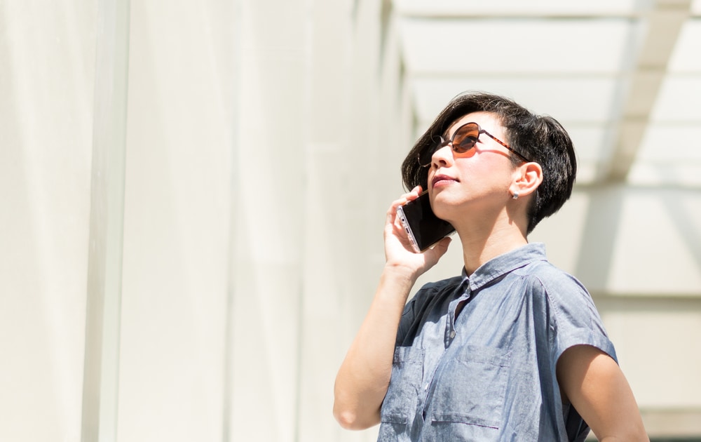 A woman wearing sunglasses and talking on the phone