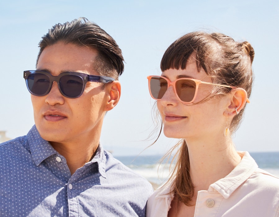 A man and woman at the beach wearing glasses with transition lenses
