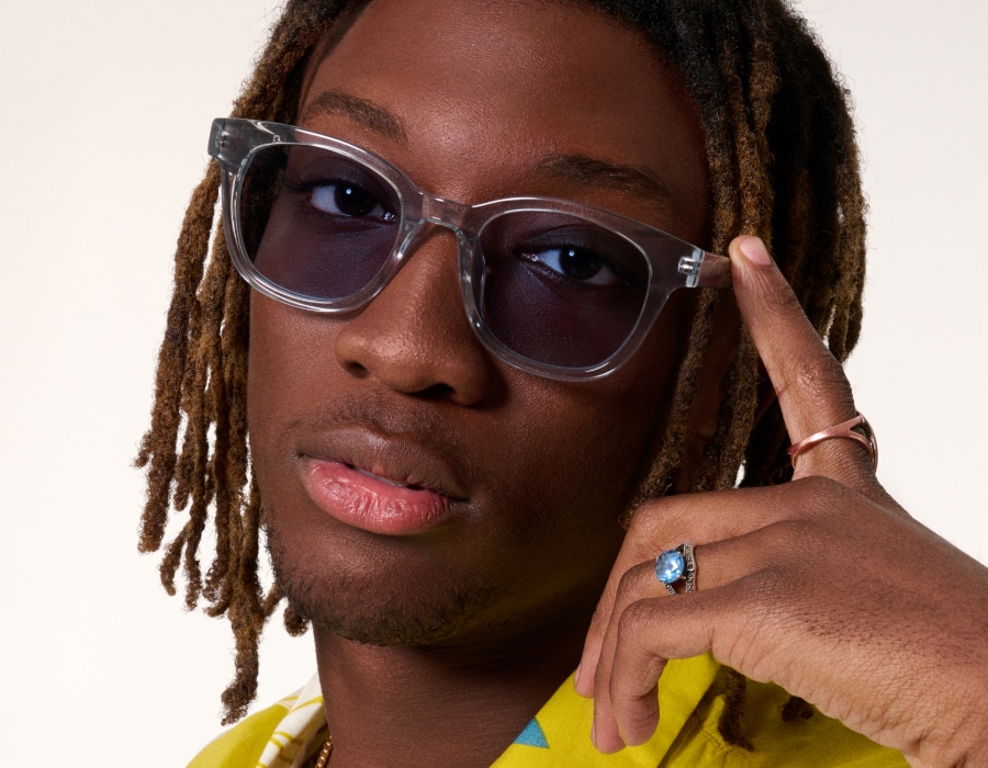 A man wearing blue-tinted sunglasses with thick translucent frames