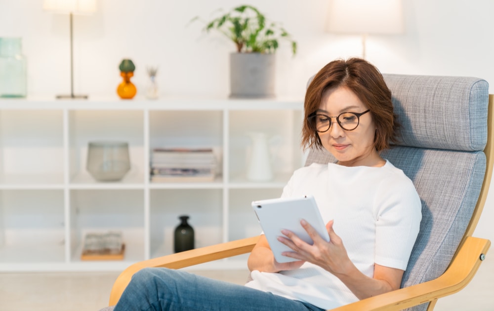 A woman wearing glasses sitting down and using a tablet