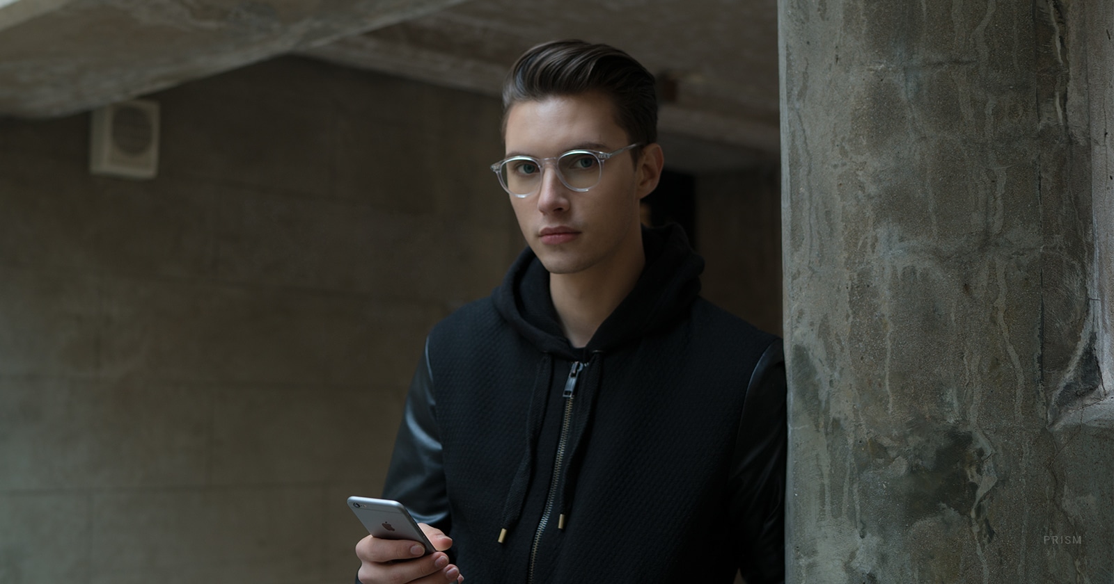 A man holding a phone wearing blue light blocking glasses