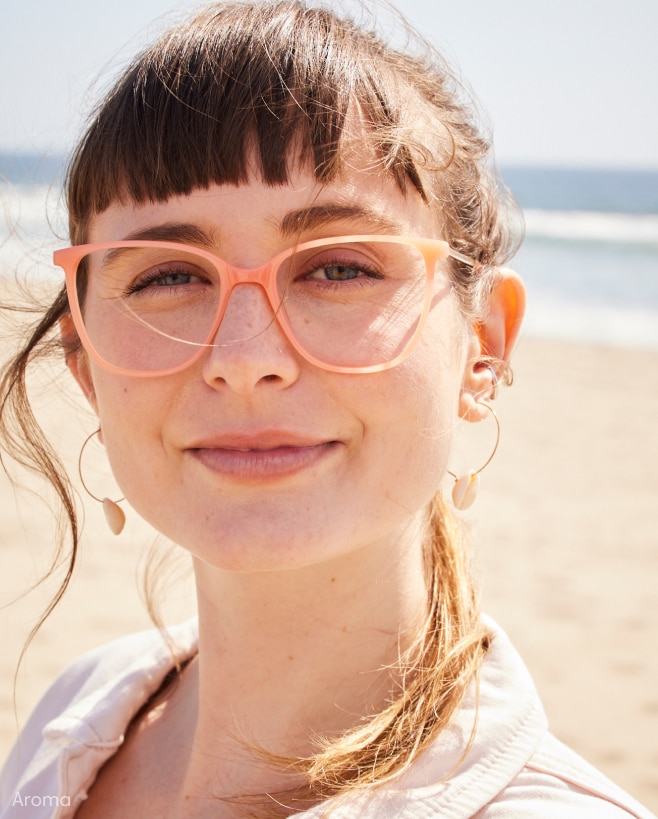A woman wearing orange eyeglasses at the beach