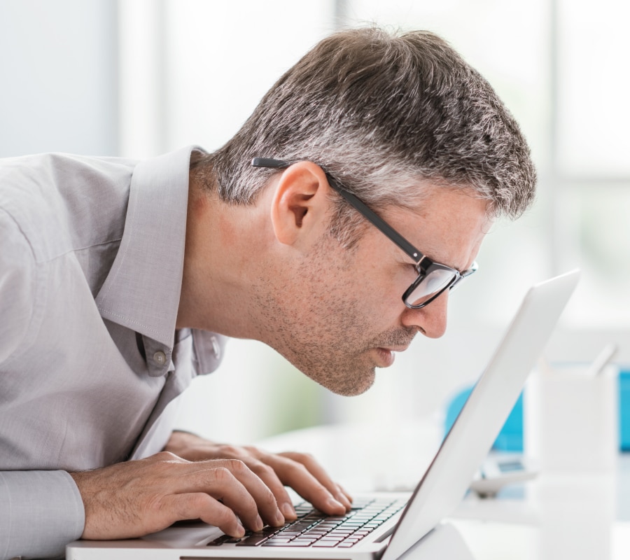 A man with nearsightedness trying to look at a laptop screen