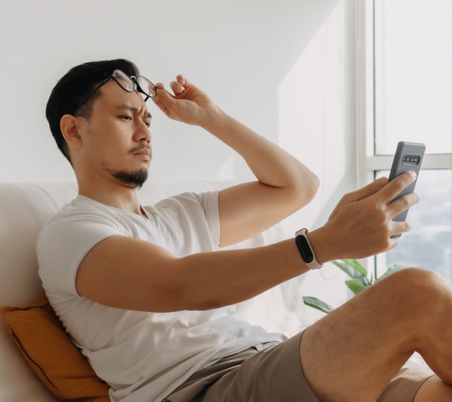 A man with farsightedness trying to look at a phone screen