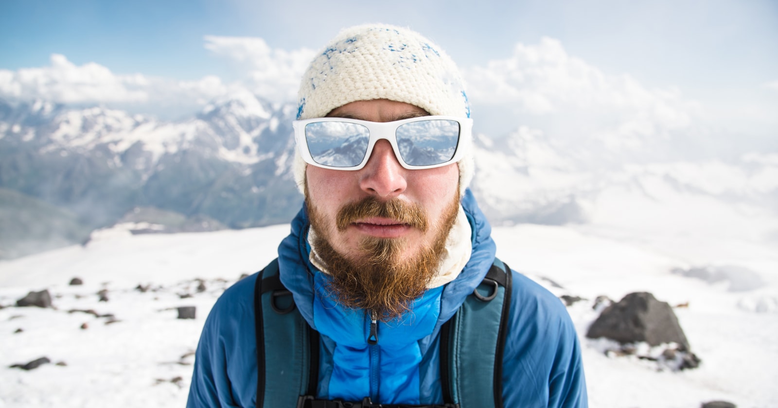 A man on a snowy mountain wearing goggle glasses