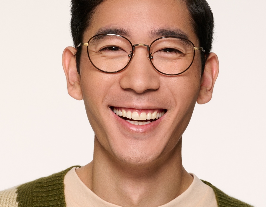 A man smiling wearing round eyeglasses