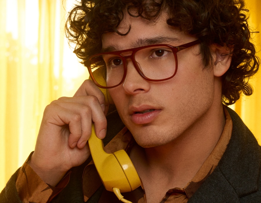 A man using a telephone wearing large eyeglasses