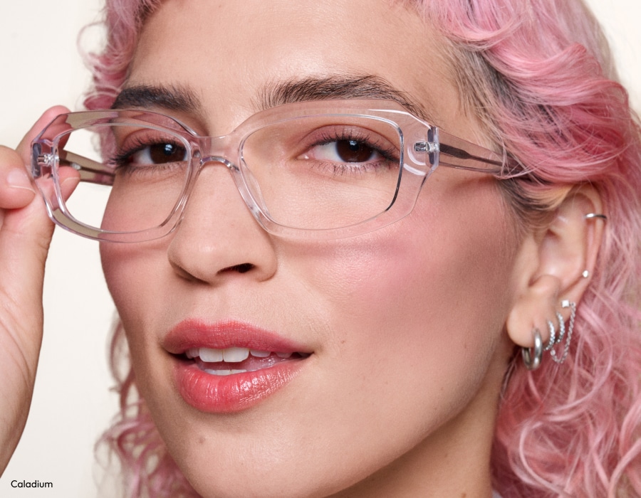 A woman with pink hair wearing eyeglasses with transparent frames