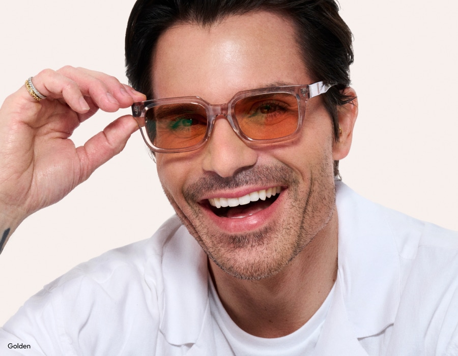 A man smiling wearing tinted eyeglasses