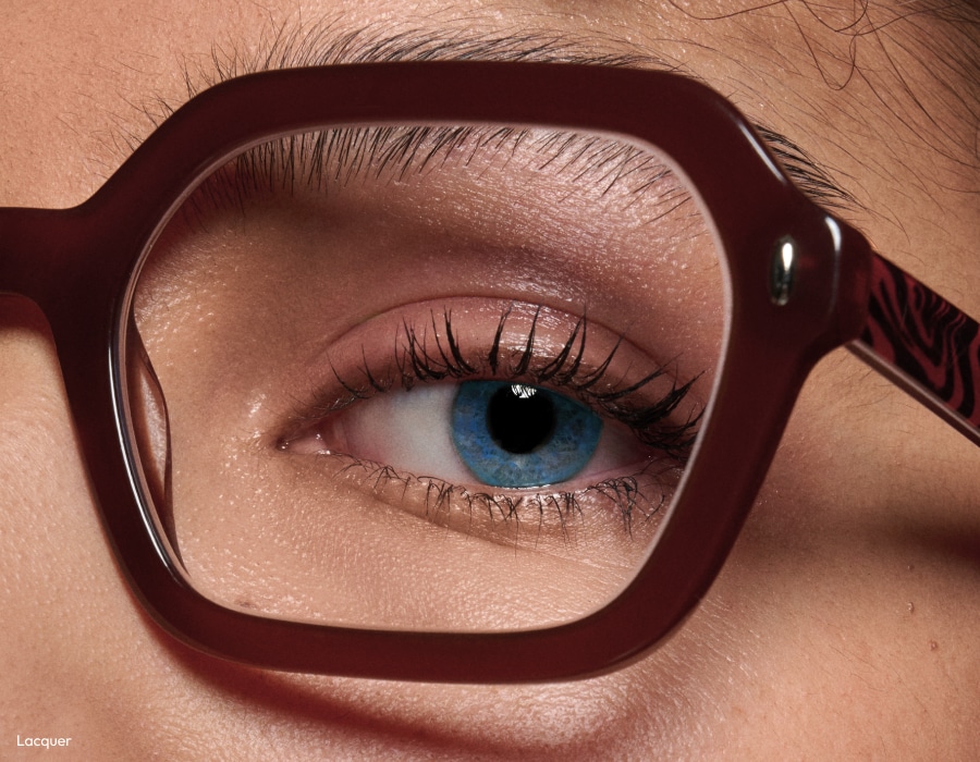 A closeup of someone's blue eye wearing thick, brown-colored eyeglasses