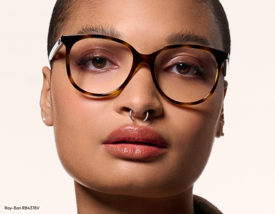 A woman with brown eyes wearing round tortoiseshell eyeglasses