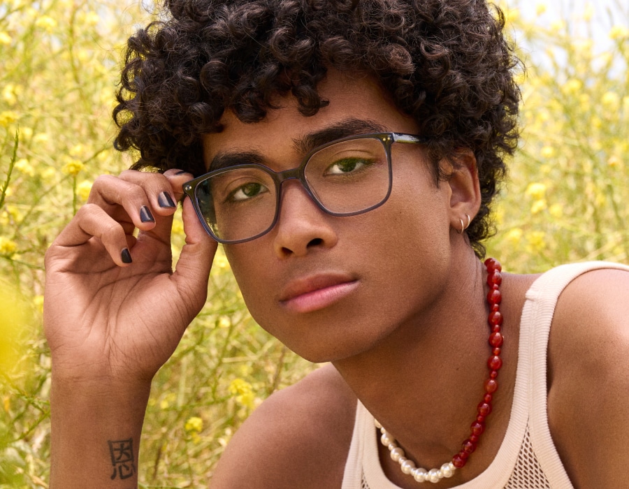 A boy in a field wearing square-shaped eyeglasses