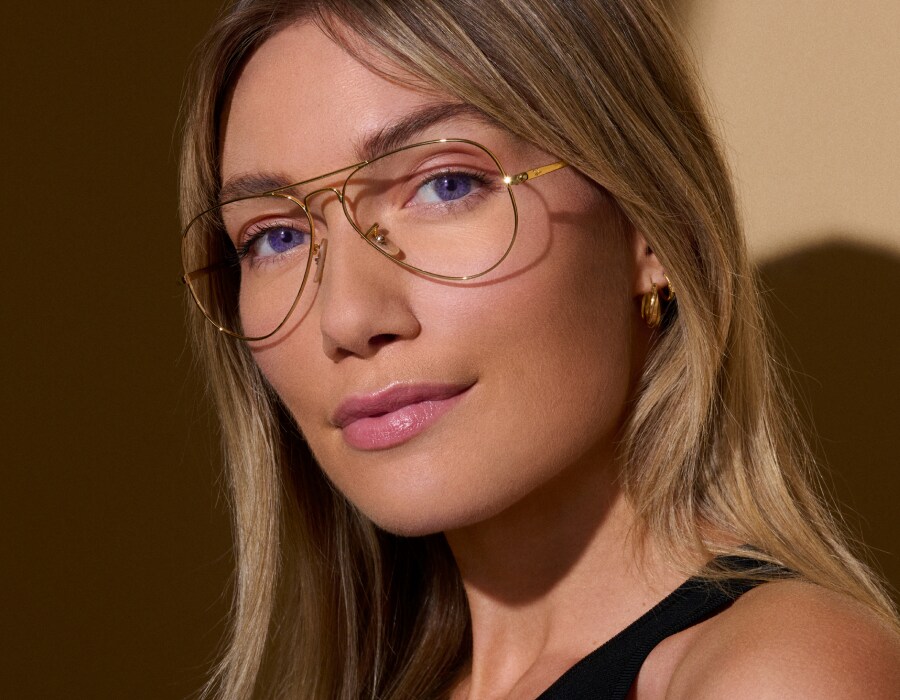 A woman with purple eyes wearing aviator-style gold-framed eyeglasses