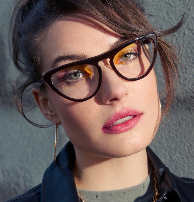 A woman with hazel eyes wearing cat-eye eyeglasses