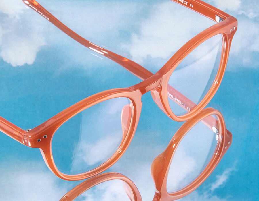 A pair of glasses with orange frames on a blue sky background