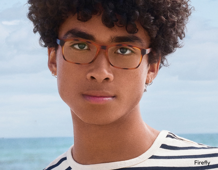 A man with curly hair wearing tortoiseshell eyeglasses