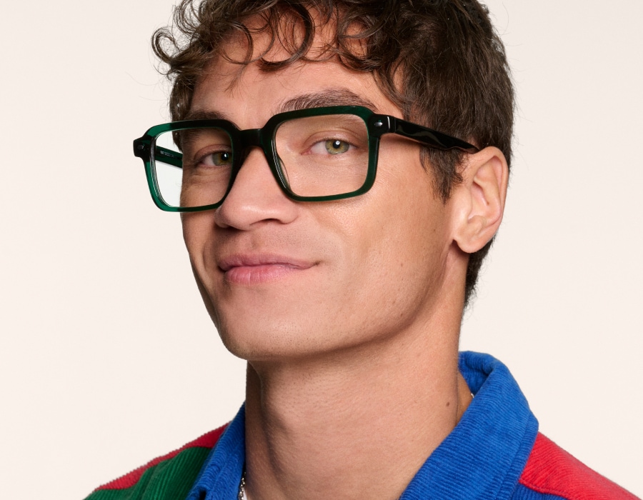 A man in a colourful shirt wearing eyeglasses with green, square-shaped frames