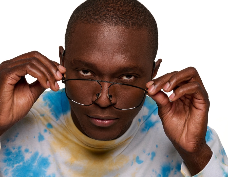 A man in a colorful sweater adjusting his glasses