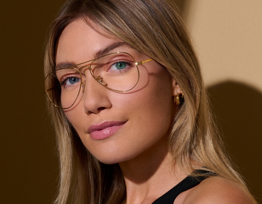 A woman with heterochromia wearing gold, wire-rim aviator style glasses frames