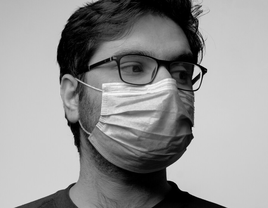 A black and white picture of a man wearing a face mask and eyeglasses