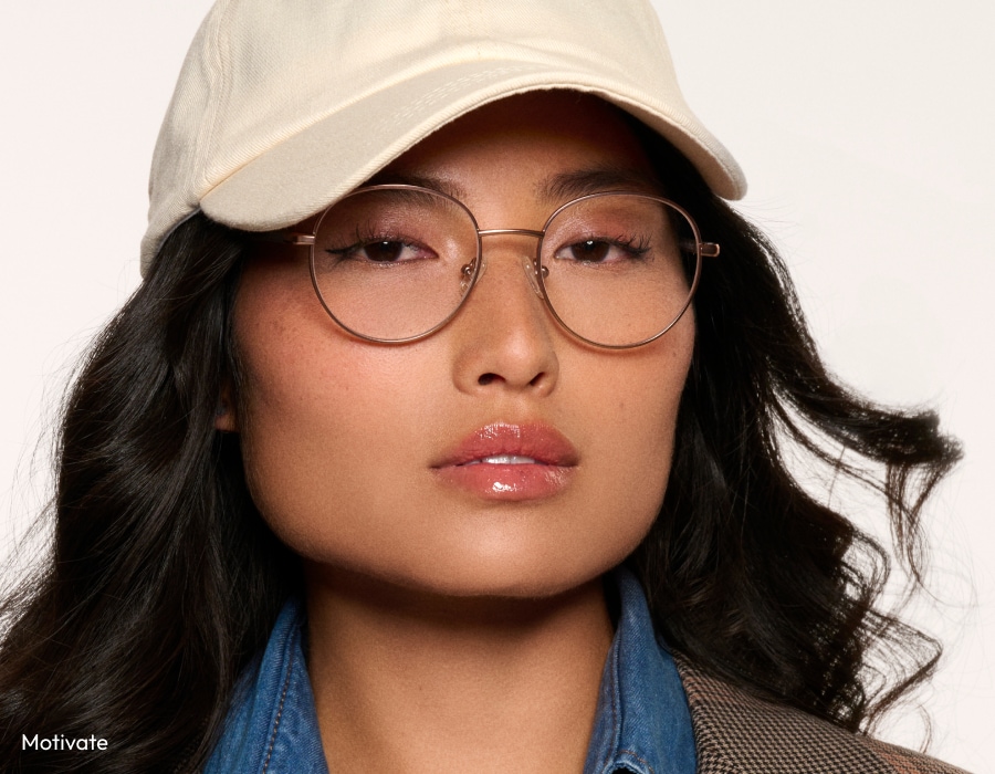 A woman wearing a cream-colored cap and round eyeglasses with anti-reflective lenses