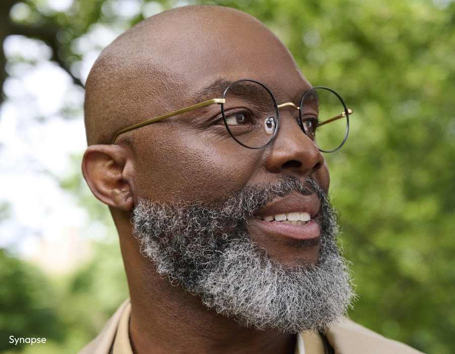 A man with a beard looking to the right wearing eyeglasses with round lenses