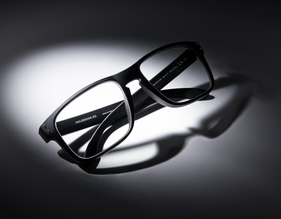 A pair of black, square eyeglasses in a dark environment