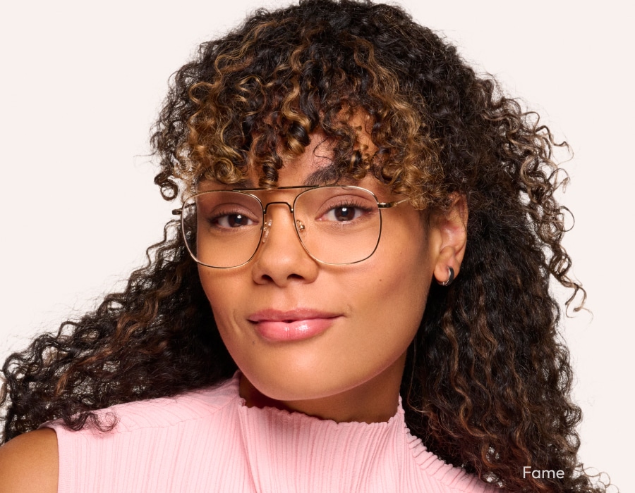 A woman in a pink shirt wearing aviator-style eyeglasses