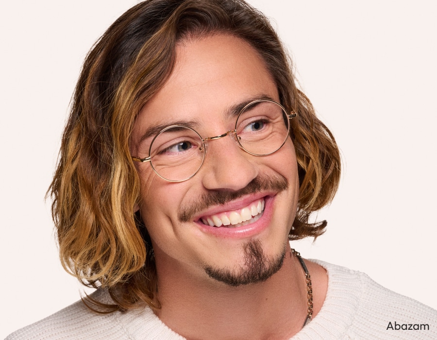 A man with long hair and a short beard wearing round eyeglasses