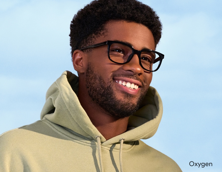 A man in front of a blue sky wearing eyeglasses with black frames