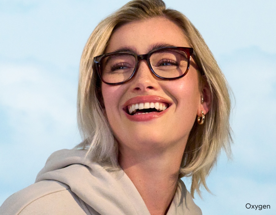 A woman smiling wearing eyeglasses with dark brown frames 