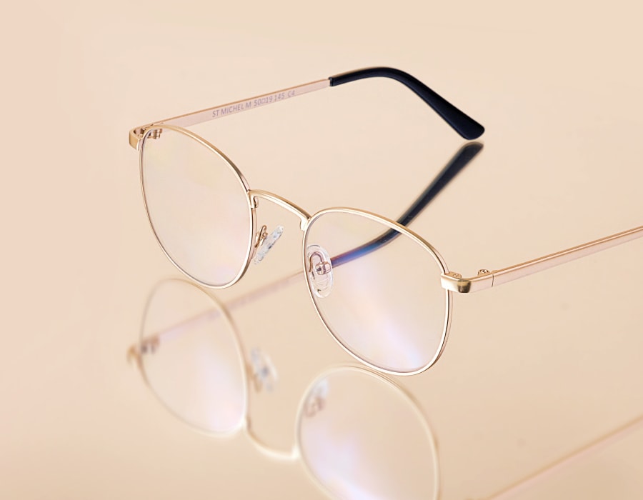 A flatlay of eyeglasses with gold-colored round frames