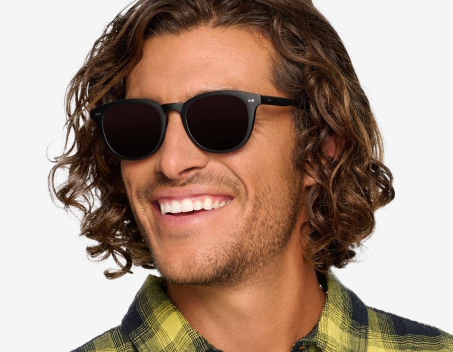 A man smiling wearing sunglasses with black frames