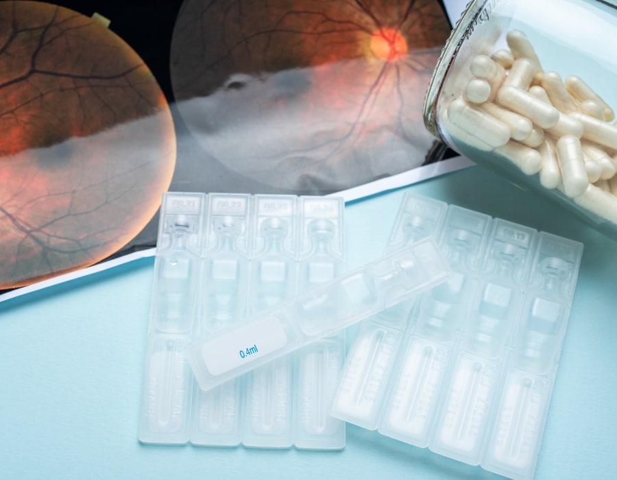 A closeup of an optemetrist's table with eye drop vials, white pills, and a photographic image of an eye