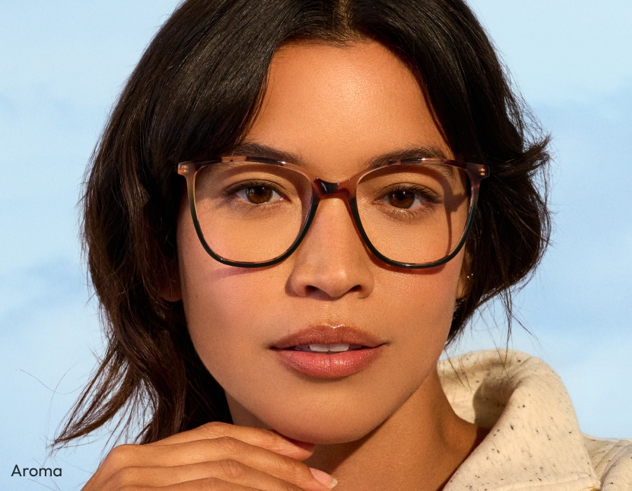 A woman looking at the camera wearing large eyeglasses with tortoiseshell frames