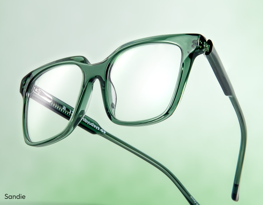 A pair of eyeglasses with green frames on a light green gradient background