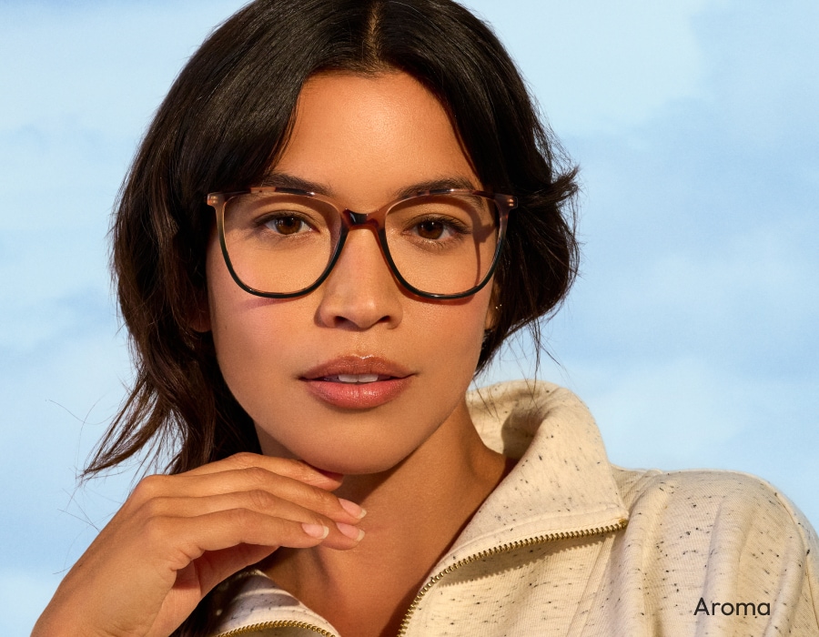 A woman looking at the camera wearing eyeglasses with tortoiseshell pattern frames