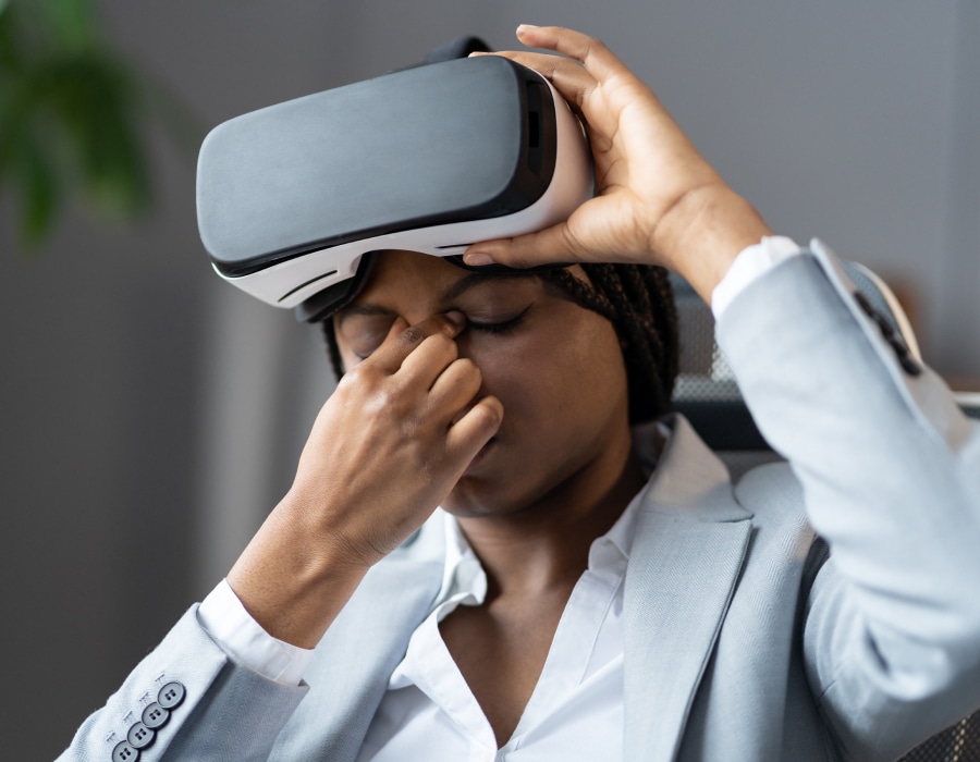 A person lifting up a VR headset and rubbing their nose bridge