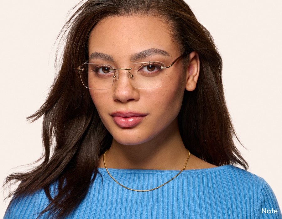 A woman in a light blue top wearing rimless square-framed eyeglasses