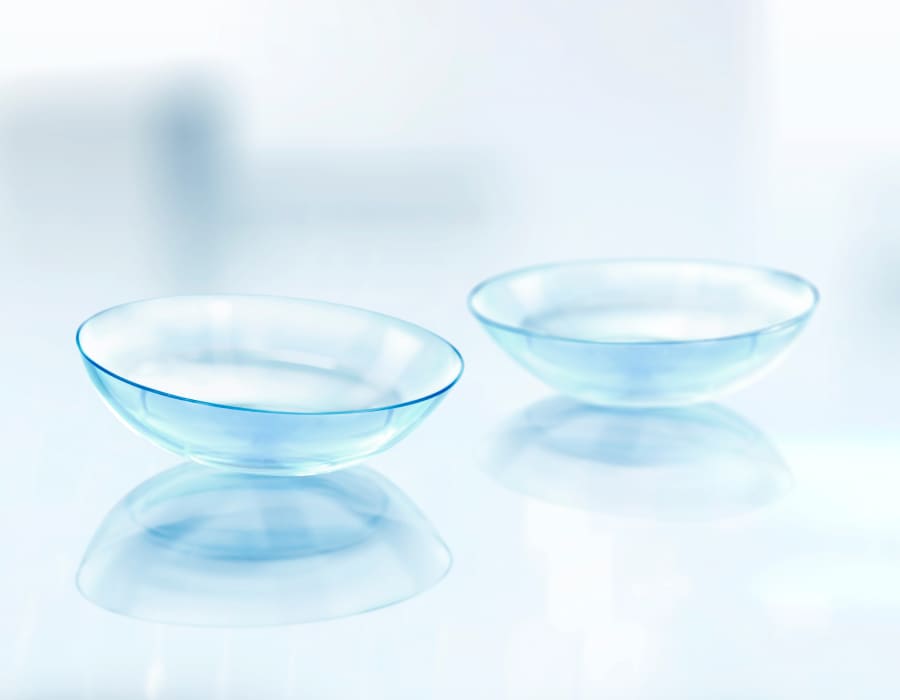 A pair of contact lenses lying on a reflective surface