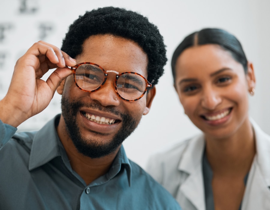 Two people with the man on the left wearing round, tortoise eyeglasses