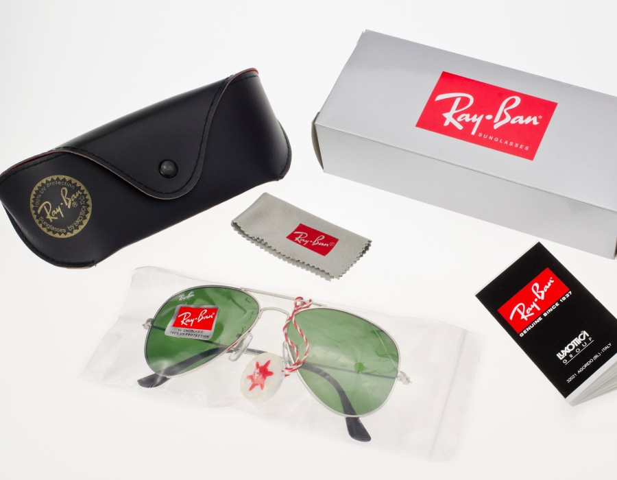 A flat-lay of a pair of Ray-Ban aviator sunglasses with the case and accessories