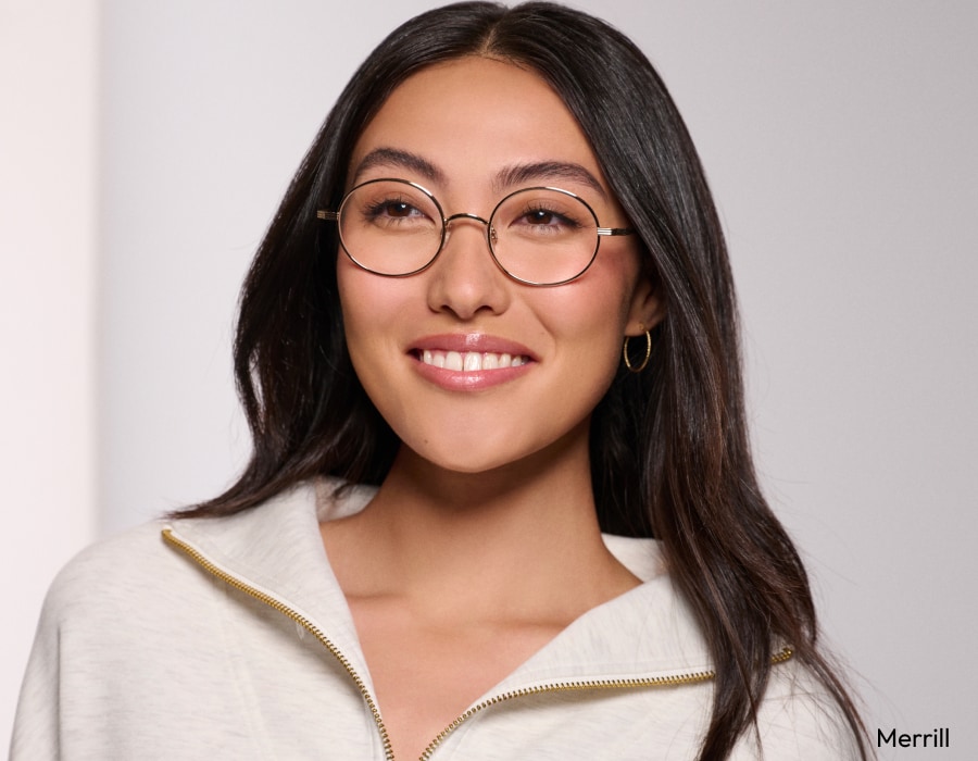 A woman smiling wearing eyeglasses with gold-colored frames