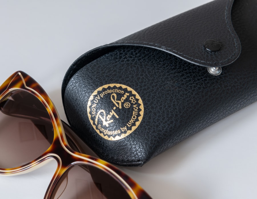 A pair of Ray-Ban sunglasses next to a Ray-Ban glasses case