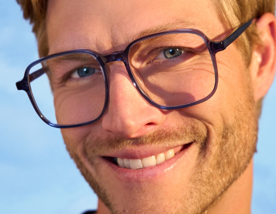 A closeup of a man's face smiling wearing eyeglasses with large square frames