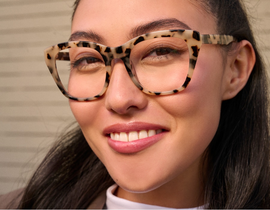 A woman smiling at the camera wearing large eyeglasses with leopard-print frames