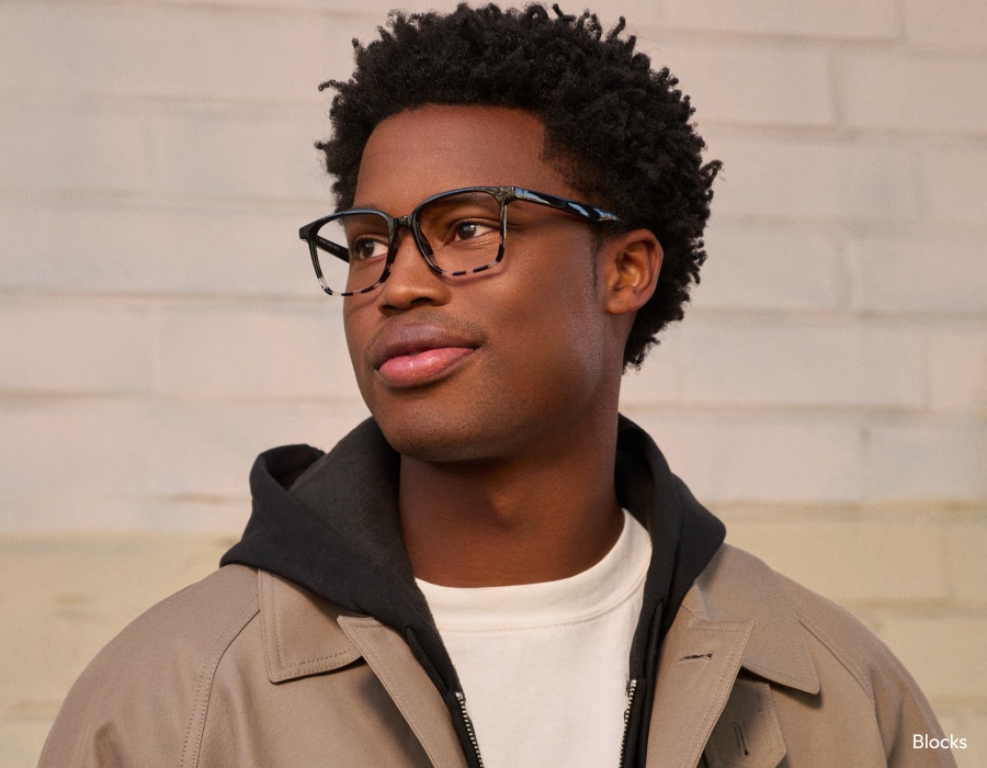 A man in a beige jacket wearing eyeglasses with tortoiseshell-patterned frames